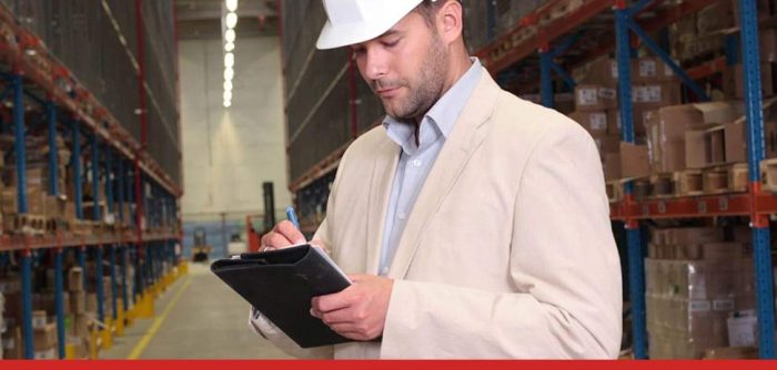 person in warehouse writing notes to illustrate a risk assessment