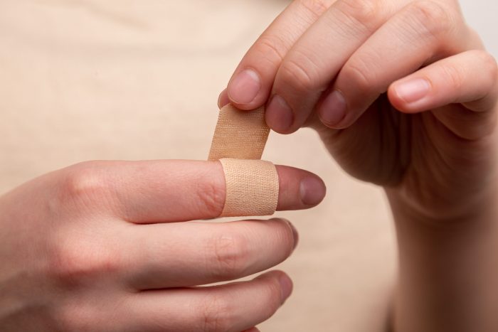 Hazards in a commercial kitchen: man putting plaster on finger