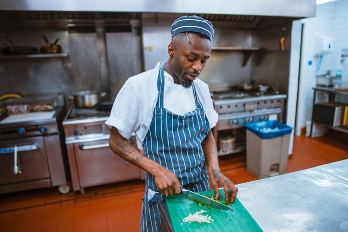 Hazards in a commercial kitchen: man chopping vegetables