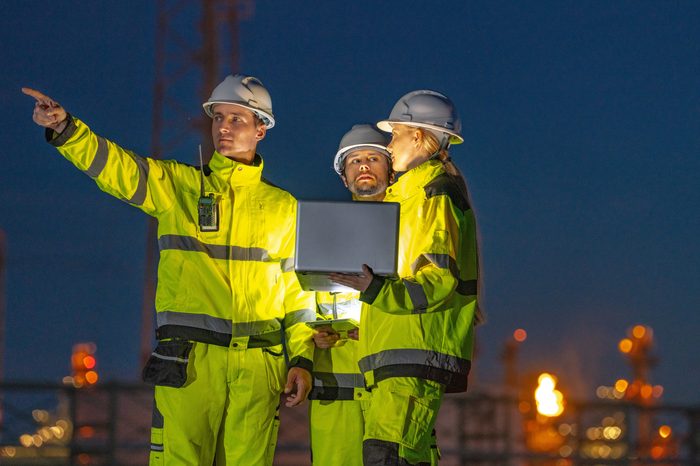 3 night workers in the dark with Hi-vis on pointing in the distance.